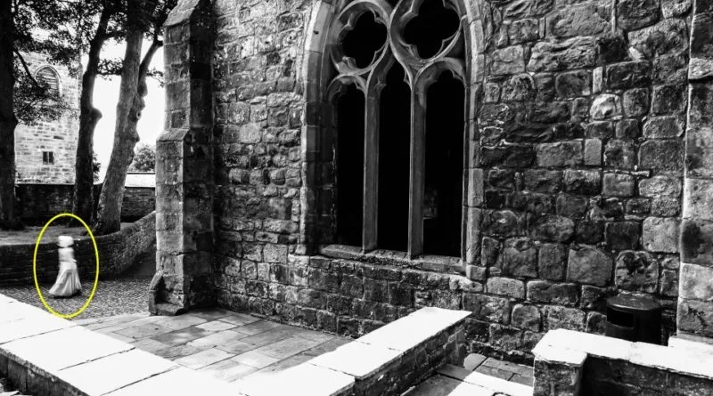 PIC FROM MERCURY PRESS (PICTURED: THE MAIN PICTURE SHOWING THE GHOST OF A LITTLE GIRL AT SKIPTON CASTLE, YORKSHIRE) A butcher has revealed a picture of what he claims is the ghost of a little girl wearing Georgian-period clothing and bonnet in the grounds of a 900-year-old castle. Mark Whitaker, 34, had visited Skipton Castle, Yorks, with his partner Amanda Ledgar, who was pregnant at the time, and had been snapping away like usual all day. It was only when he got back home in Colne, Lancs, that the then dad-to-be and now dad-of-one, noticed the three-foot tall ghostly figure walking by the castle. The image shows a clear figure in a white floor length period dress and a bonnet that appears to float where her head would be - though the eerie child has no visible arms or neck. Mark claims the image still sends a shiver down his spine whenever he looks at it but has now revealed it to see what others think. SEE MERCURY COPY